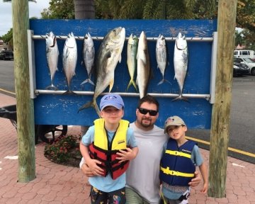 a guy with two kids in front of the sailfish marina sign